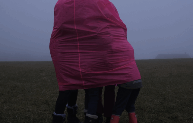 Sur l'image, il y a plusieurs personnes de tailles différentes cachées sous tissu rose