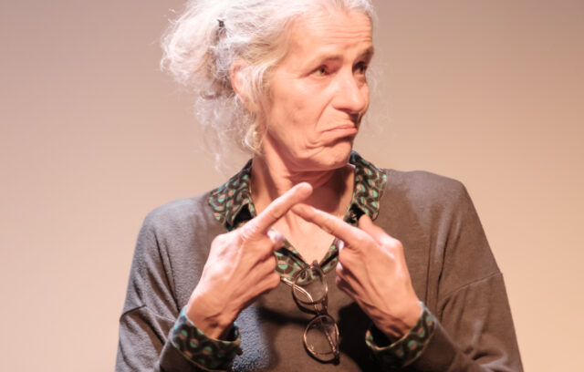 Une comédienne est en train de signer en langue des signes française.